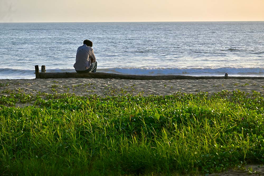 Man sitting on a bench looking out at the ocean