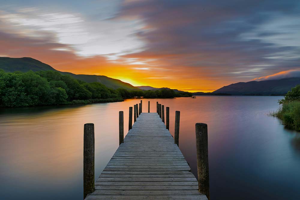 Sunset over a calm lake with a wooden pier